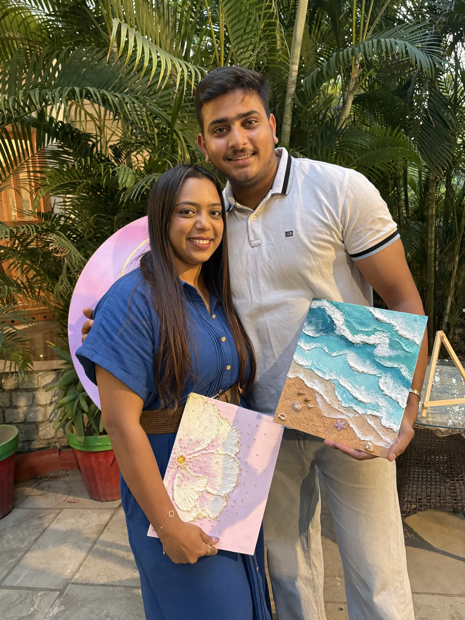 A couple holding their floral and beach canvases